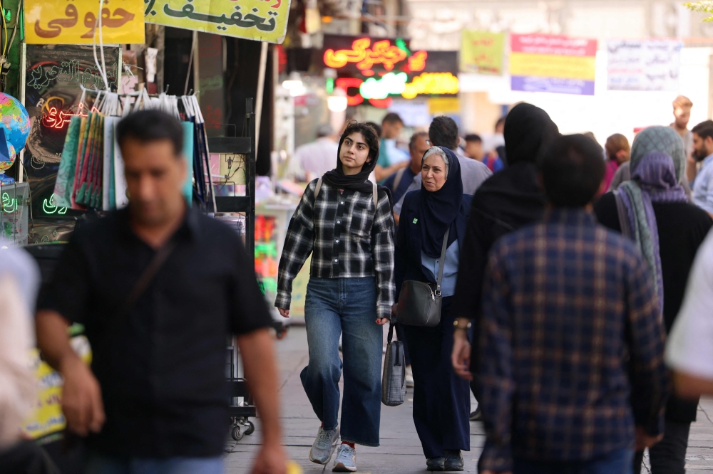 Iranians walk along a busy street in Tehran on September 28, 2025. (Photo by Atta Kenare / AFP)