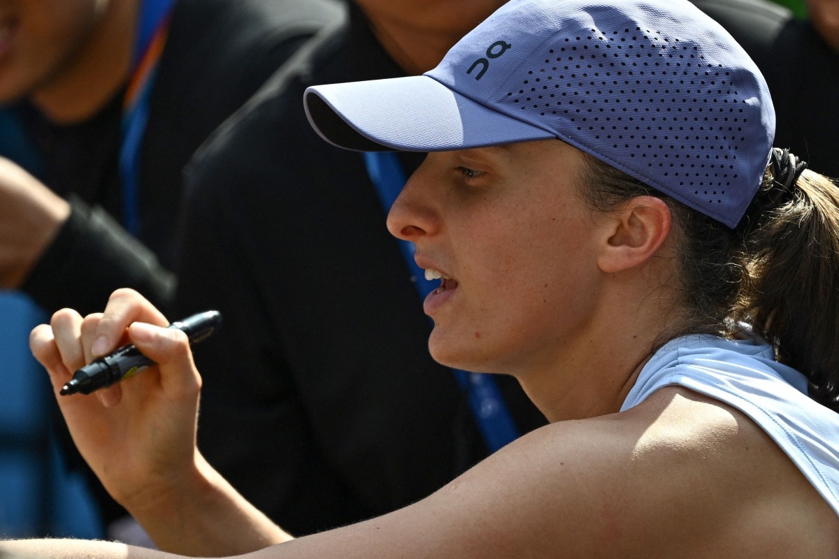 Poland's Iga Swiatek signs autographs for fans after her women's singles match against Colombia痴 Camila Osorio at the China Open tennis tournament in Beijing on September 29, 2025. (Photo by Pedro Pardo / AFP)