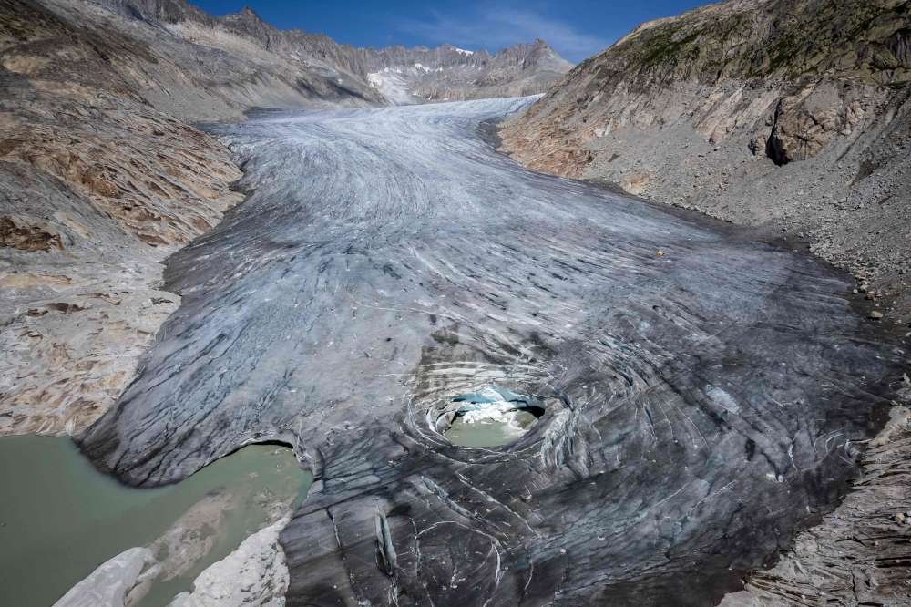 (Files) An aerial photograph taken on August 24, 2023 above Gletsch, in the Swiss Alps shows a hole in the part of the Rhone Glacier revealing its glacial lake due to the melting of the glacier.  (Photo by Fabrice Coffrini / AFP)