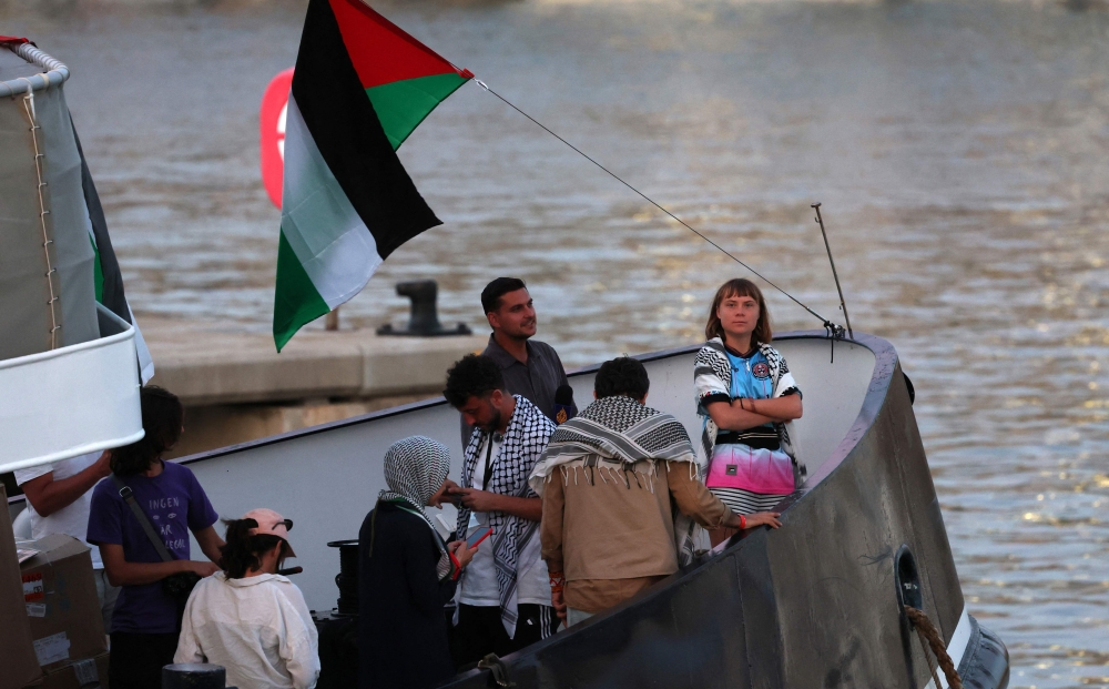 (Files) Swedish climate activist Greta Thunberg (R) is seen on board of a vessel of a civilian flotilla remains moored at Barcelona port on September 1, 2025. (Photo by Lluis Gene / AFP)
