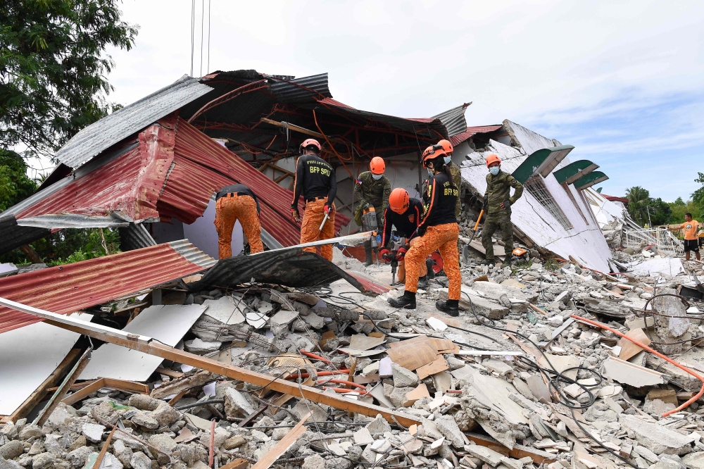 Rescuers search for three people who were reported missing under the rubble of a collapsed building in Bogo City on October 1, 2025. (Photo by Ted Aljibe / AFP)
