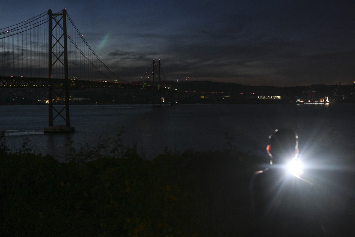 This photograph shows the 25th April bridge over the Tagus river with the lights off following a massive power cut affecting the entire Iberian peninsula and the south of France, in Lisbon on April 28, 2025. Photo by Patricia DE MELO MOREIRA / AFP.

