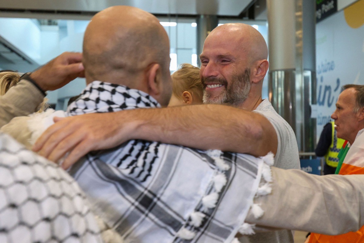 Tadhg Hickey (centre right) one of a group of Irish activists returning, is greeted by supporters as they arrive at Dublin Airport on October 7, 2025, after being deported from Israel. (Photo by Paul Faith / AFP)
