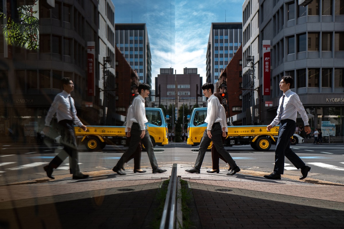 Pedestrians are seen reflected in glass as they walk in the Ginza district of Tokyo on October 8, 2025. (Photo by Philip FONG / AFP)