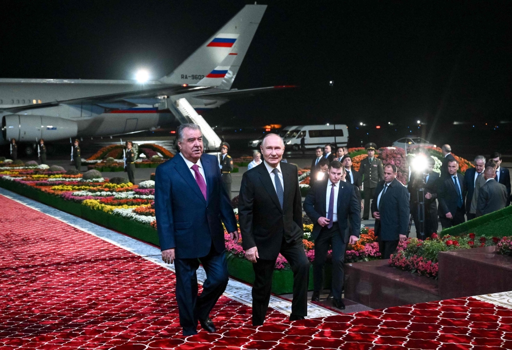 In this pool photograph distributed by the Russian state agency Sputnik, Russia's President Vladimir Putin (right) walks with his Tajik counterpart Emomali Rakhmon upon the Russian leader's arrival at the airport in Dushanbe on October 8, 2025. (Photo by Kristina Kormilitsyna / POOL / AFP)
