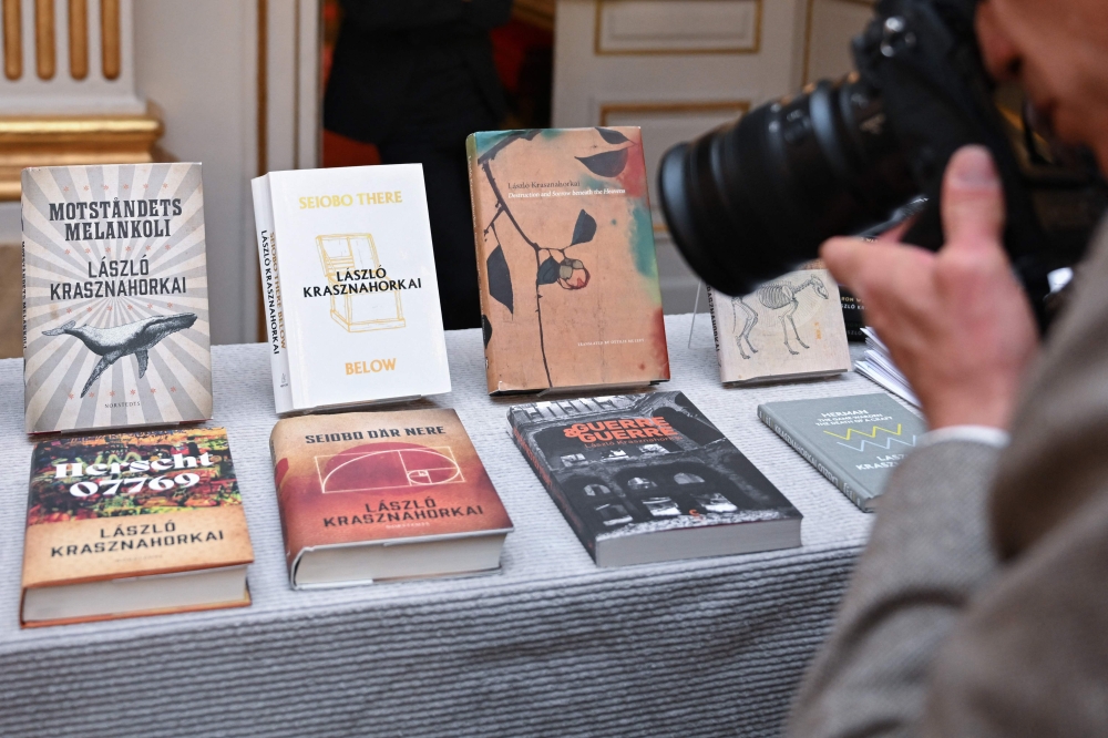 A photographer takes photos of Books of Hungarian writer Laszlo Krasznahorkai, the winner of the 2025 Nobel Prize in Literature, on display at the Swedish Academy in Stockholm, Sweden, on October 9, 2025. (Photo by Jonathan Nackstrand / AFP) 