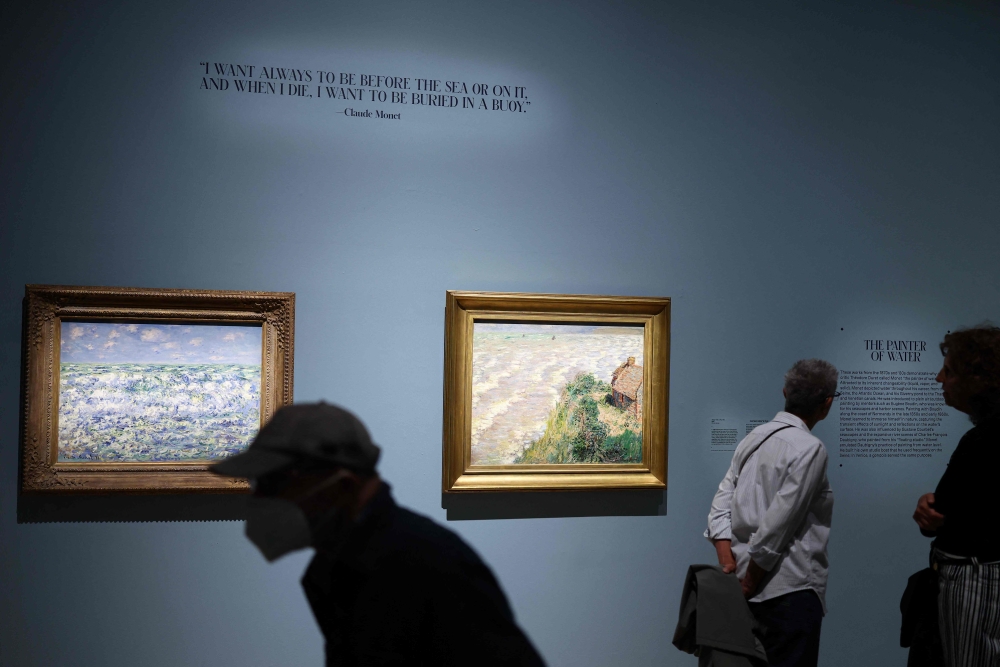 People view paintings by French artist Claude Monet on display at the 