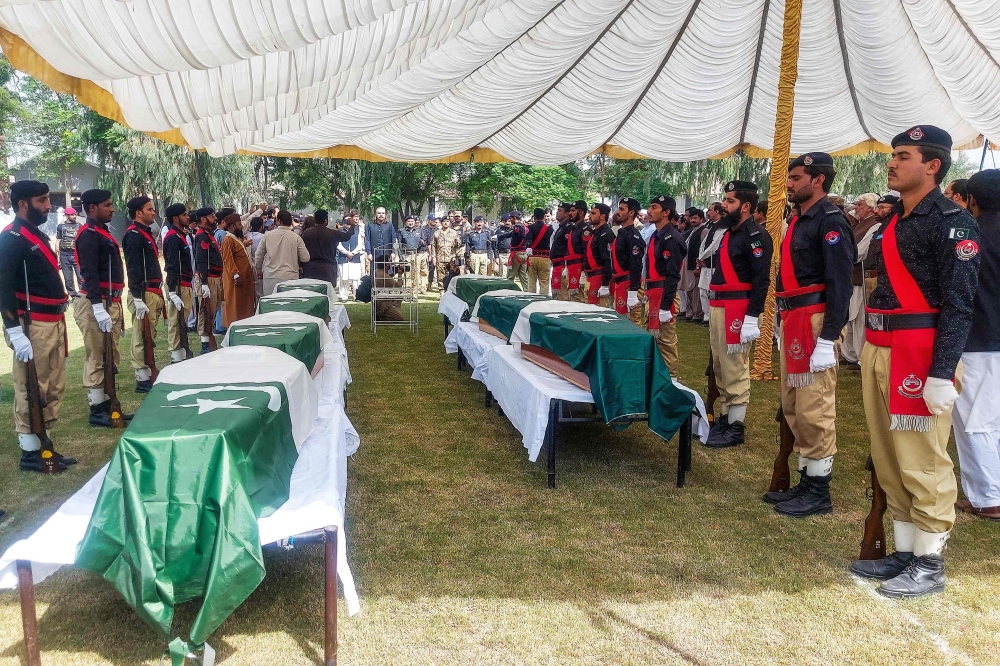 Policemen stand by the coffins of slain police personnel during a funeral ceremony at Dera Ismail Khan in Khyber Pakhtunkhwa province on October 11, 2025. (Photo by Mohammad Kashif / AFP)
 