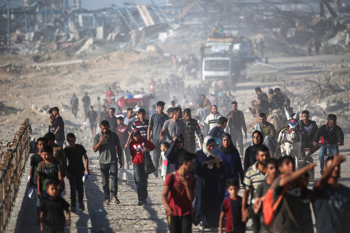 Palestinians walk along the “Netzarim corridor” in central Gaza yesterday to return to their homes. (AFP)