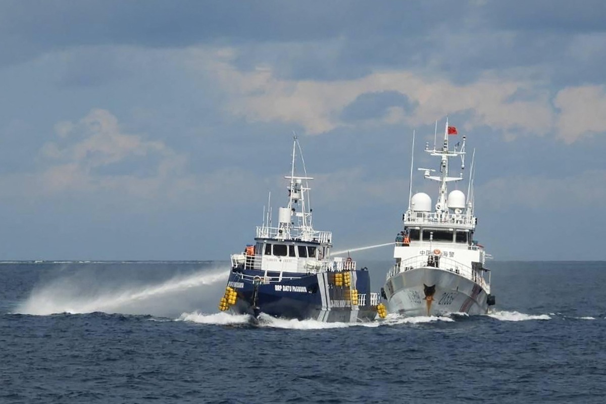 This handout photo taken and released on October 12, 2025 by the Philippine Coast Guard shows a China Coast Guard ship (R) deploying water cannon as a Philippine Bureau of Fisheries vessel (L) is seen alongside during an incident near Thitu island in disputed waters of the South China Sea. Photo by Handout / Philippine Coast Guard (PCG) / AFP