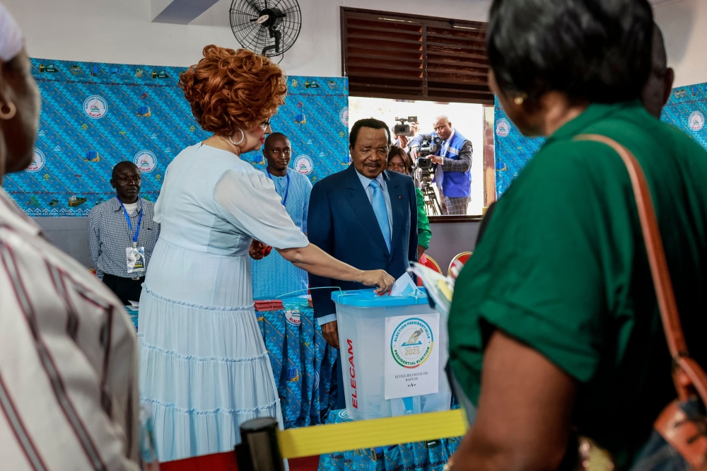 Paul Biya, President of Cameroon and presidential candidate for the Cameroon People's Democratic Movement (CPDM), watches as Cameroon First Lady Chantal Biya casts her ballot at a polling station in Yaounde on October 12, 2025 during Cameroon's presidential election. (Photo by Daniel Beloumou Olomo / AFP)