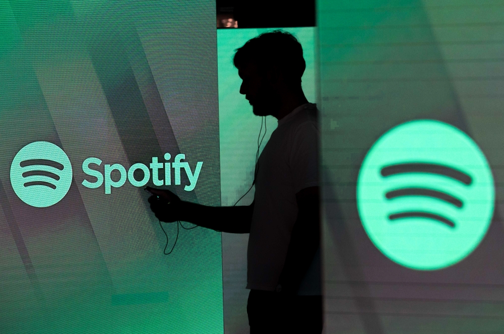 File: A man checks his smartphone whilst standing amongst illuminated screens bearing the Spotify Technology SA logo in this arranged photograph in London, UK, on Tuesday, June 26, 2018. (Photo by Chris Ratcliffe/Bloomberg)
