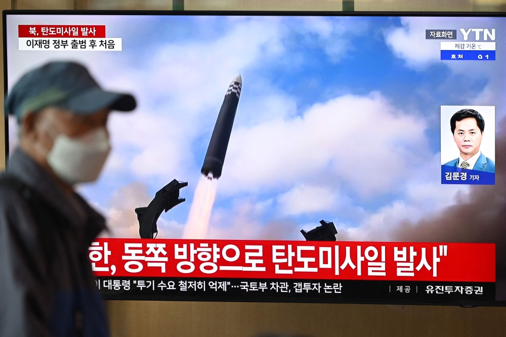 A man walks past a television screen showing a news broadcast with file footage of a North Korean missile test, at a train station in Seoul on October 22, 2025. (Photo by Jung Yeon-je / AFP)