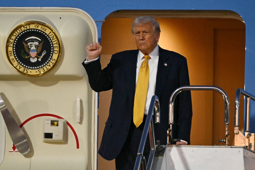 US President Donald Trump gestures as he prepares to alight from Air Force One upon arrival at Haneda Airport in Tokyo on October 27, 2025. (Photo by Philip Fong / AFP)