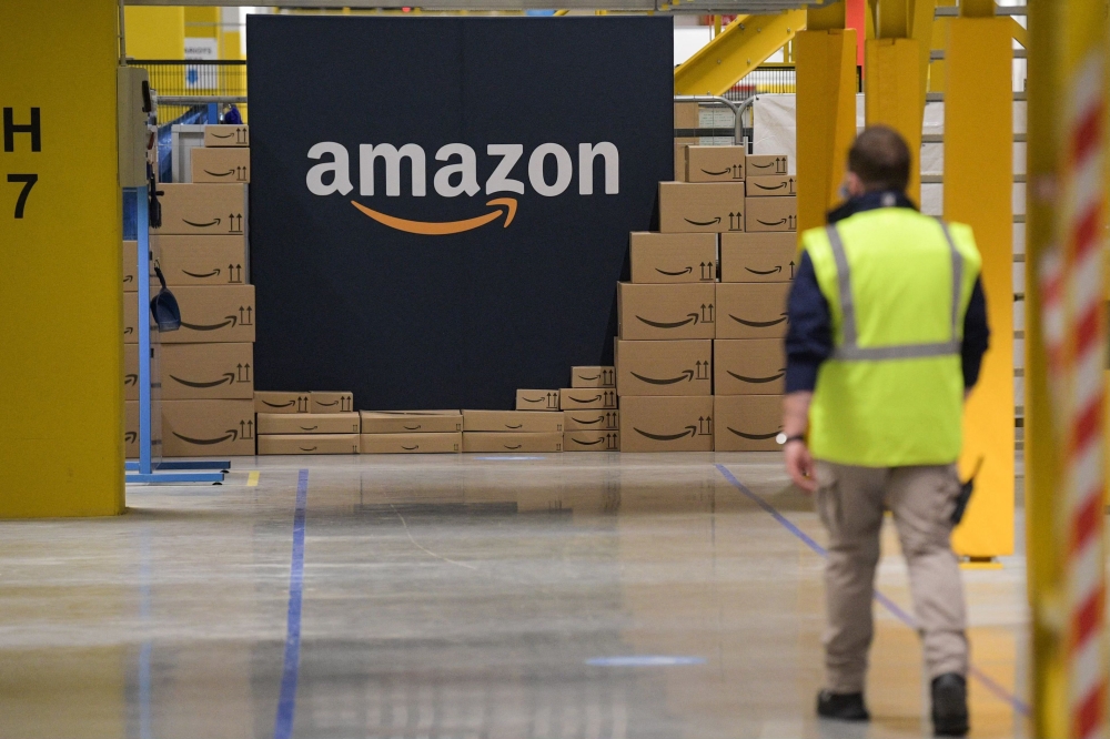 Files: An US giant Amazon employee passes by its logo on the opening day of the new distribution center in Augny, eastern France, on September 23, 2021. (Photo by Sebastien Bozon / AFP)