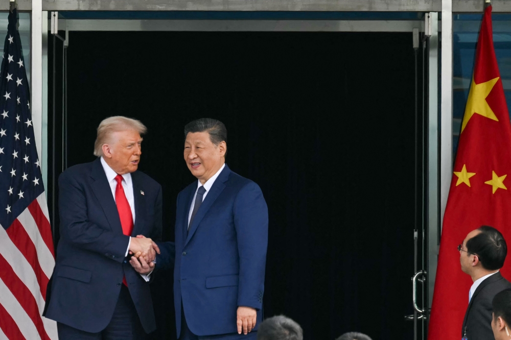 US President Donald Trump (L) and China's President Xi Jinping shake hands as they leave after their talks at the Gimhae Air Base on October 30, 2025. (Photo by Andrew Caballero-Reynolds / AFP)