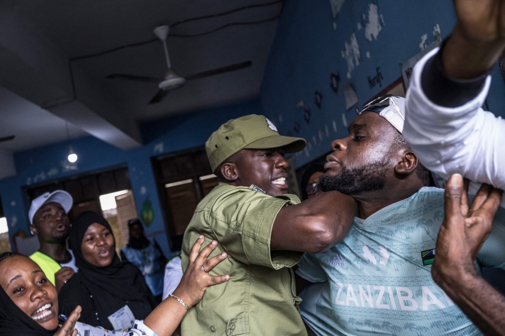 A Tanzanian police officer stops a man accused by electoral officials of attempting to taint the voting process at a polling station in Stone Town on October 29, 2025, during Tanzania presidential elections. Photo by Marco Longari / AFP
