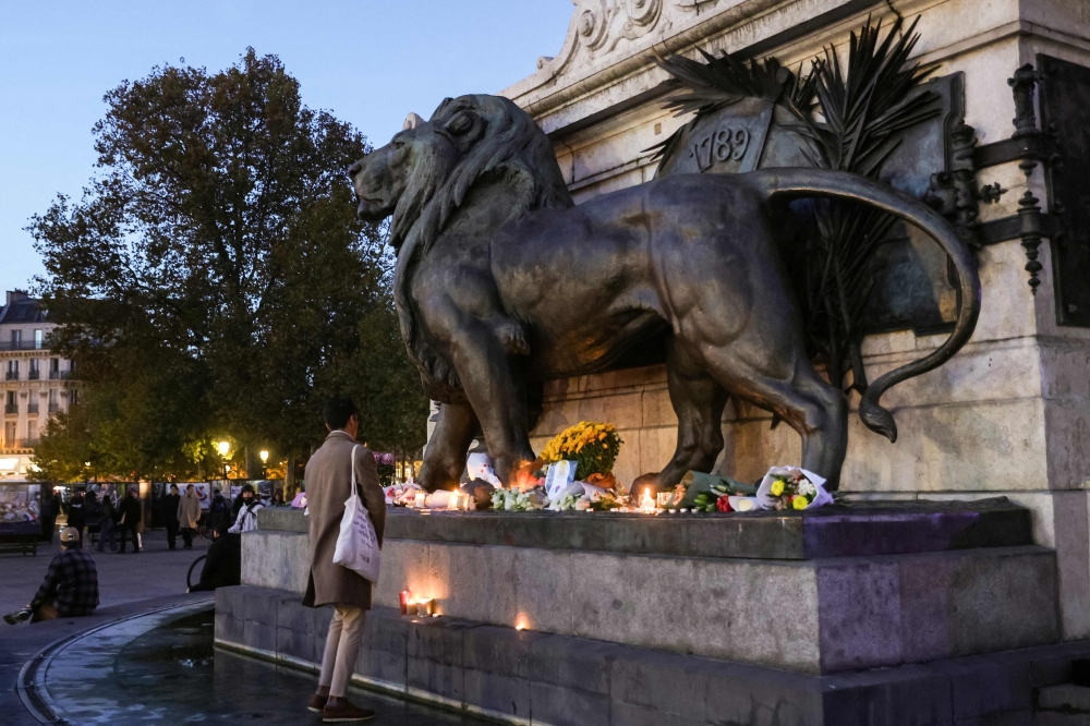 A man stands in front of a makeshift memorial in tribute of the victims of Paris' attacks of November 13, 2015, at the place de la Republique, in Paris, on November 8, 2025. (Photo by Geoffroy Van Der Hasselt / AFP)