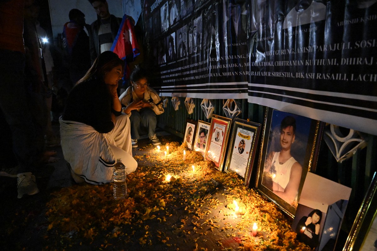 Family members of those killed in September anti-corruption protests take part in a candlelight vigil in front of the fire-damaged parliament building in Kathmandu on November 9, 2025. (Photo by Prakash Mathema / AFP)
