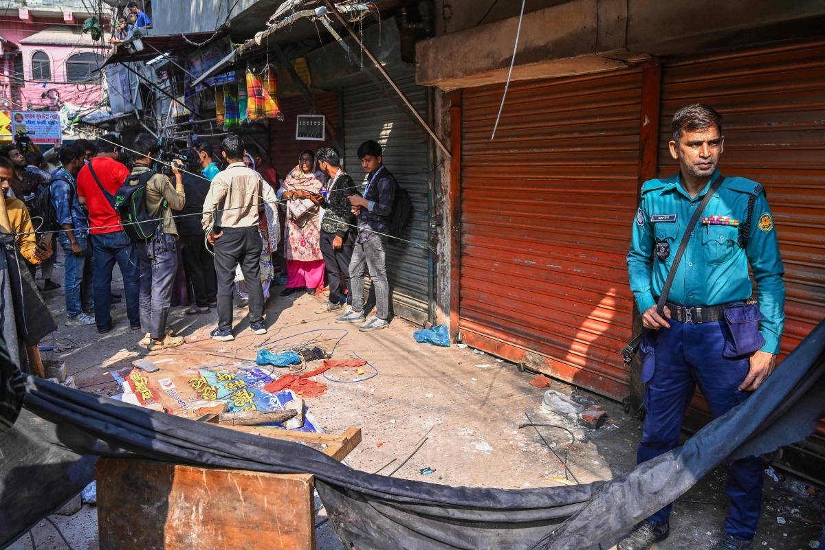 A police personnel stands guard near the rubble that fell from a damaged building following an earthquake in Old Dhaka on November 21, 2025. (Photo by Munir UZ ZAMAN / AFP)