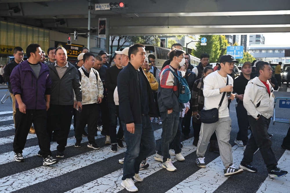 Tourists from China cross a road in the Ginza shopping district in Tokyo on November 22, 2025. (Photo by Greg Baker / AFP)