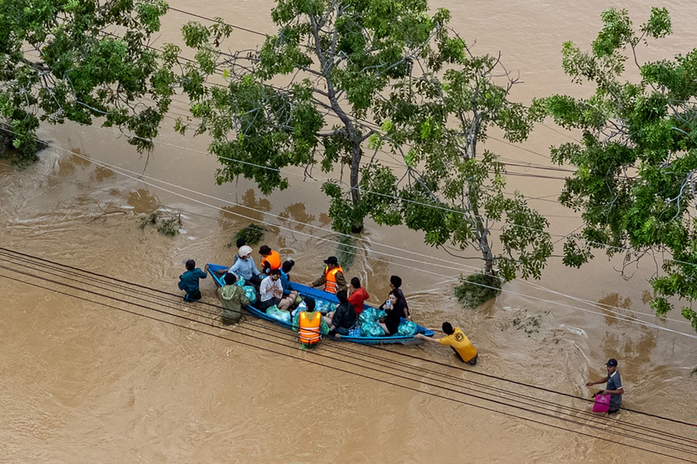 This aerial photo shows people wading through floodwaters in Phan Rang in southern Vietnam's Khanh Hoa province on November 21, 2025. (Photo by Bao Quan / AFP)