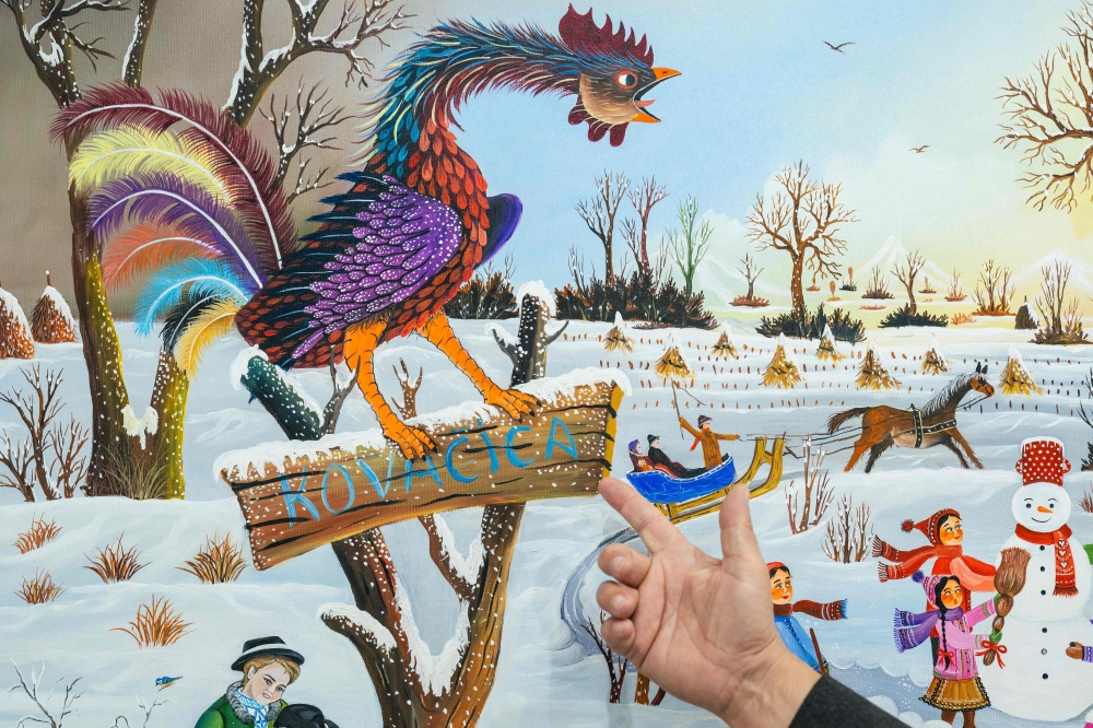 Gallery owner Paul Babka points at details of naive art paintings in Kovacica, northern Serbia, on October 16, 2025. (Photo by Andrej Isakovic / AFP) /
