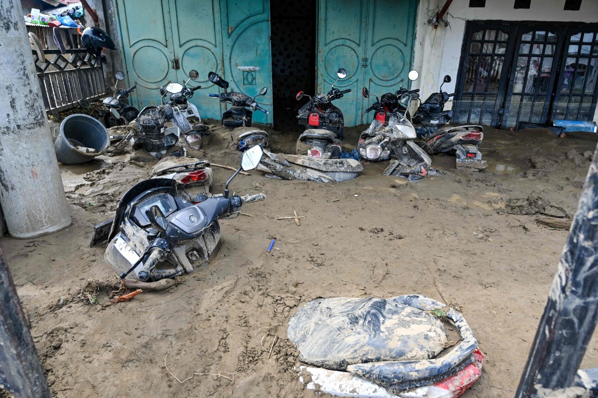 A general view shows motorcycles trapped in mud after the flash floods in Meureudu, Pidie Jaya district of Indonesia's Aceh province, on November 28, 2025. (Photo by Chaideer MAHYUDDIN / AFP)
