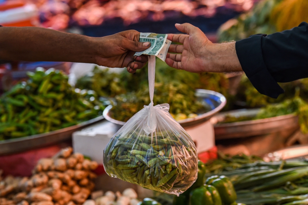 File photo: A customer buys vegetables from a stall at a market in Karachi on July 3, 2023. (Photo by Asif HASSAN / AFP)