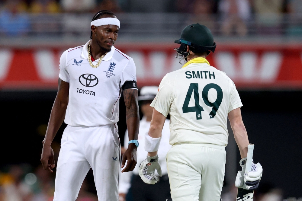 Australia's captain Steve Smith (R) reacts with England's Jofra Archer on day four of the second Ashes cricket Test match between Australia and England on December 7, 2025. (Photo by David Gray / AFP) 