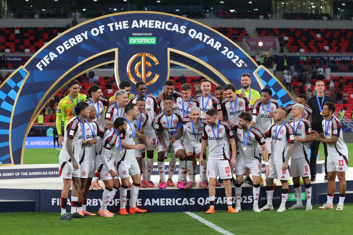 Flamengo's Bruno Henrique lifts the trophy as he celebrates with teammates after wining the FIFA Derby of the Americas match between Cruz Azul and Flamengo at Ahmad Bin Ali Stadium in Doha on December 10, 2025. (Photo by Karim JAAFAR / AFP)
