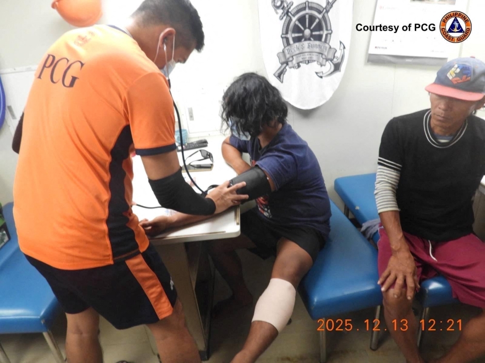 This handout photo from the Philippine Coast Guard (PCG) received on December 13, 2025, shows coast guard personnel attending to injured fishermen after an incident with China Coast Guard near Sabina Shoal in the South China Sea. (Photo by Handout / Philippine Coast Guard (PCG) / AFP) 