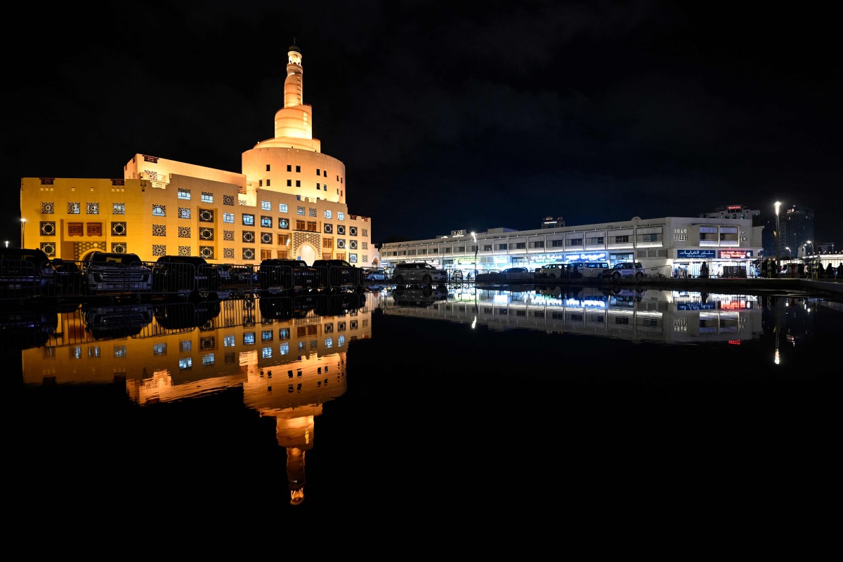 The Abdullah Bin Zaid al-Mahmoud Islamic Cultural Centre is reflected in a pool of water on a rainy day in the Qatari capital Doha on December 16, 2025. Photo by Mahmud HAMS / AFP