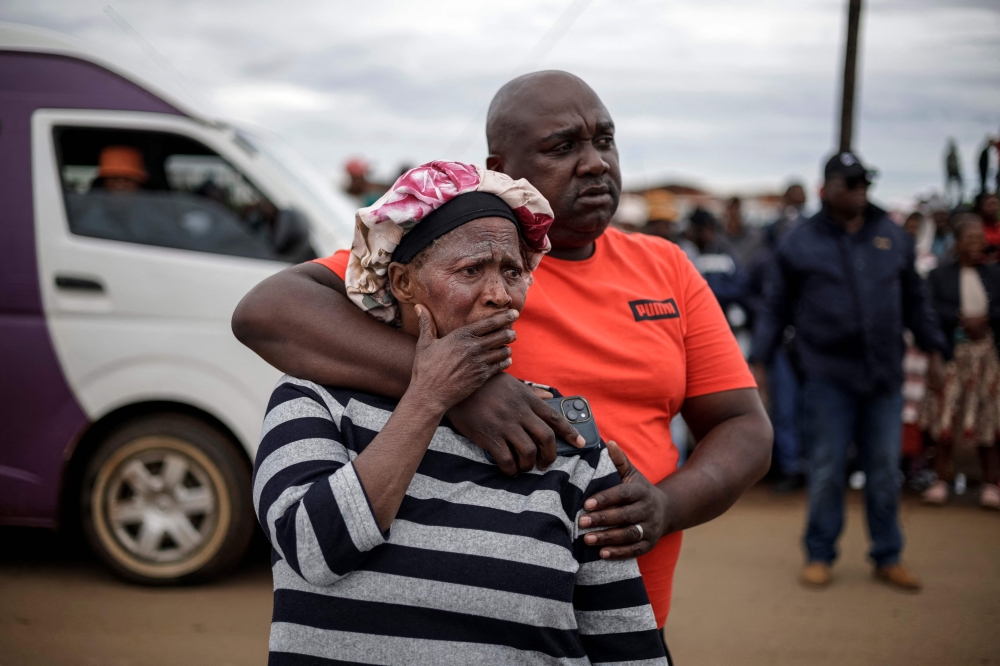 Family members of a victim react at the scene of an attack in Bekkersdal on December 21, 2025. Nine people were killed when gunmen opened fire outside Johannesburg early on December 21, 2025. (Photo by Emmanuel Croset / AFP)