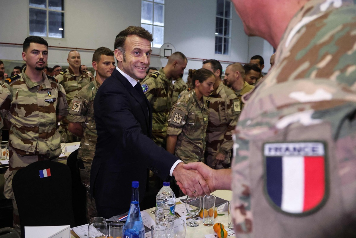 French President Emmanuel Macron shakes hands with a soldier during a Christmas diner with troops of the 5th Cuirassier Regiment's base in Zayed Military City, near Abu Dhabi, on December 21, 2025.(Photo by Ludovic MARIN / AFP)
