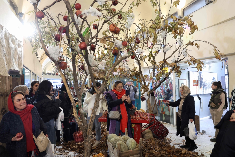 Iranians celebrate with Yalda decoration in northern Tehran on December 20, 2025, in preparation for the annual festival of Yalda. (Photo by -STR / AFP)