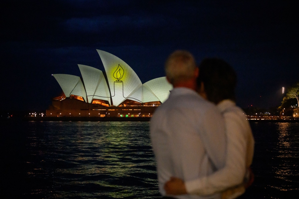 The Sydney Opera House is illuminated with candlelights in Sydney on December 21, 2025, as part of a national day of reflection honouring the victims of the Bondi Beach terrorist attack. (Photo by George Chan / AFP)
