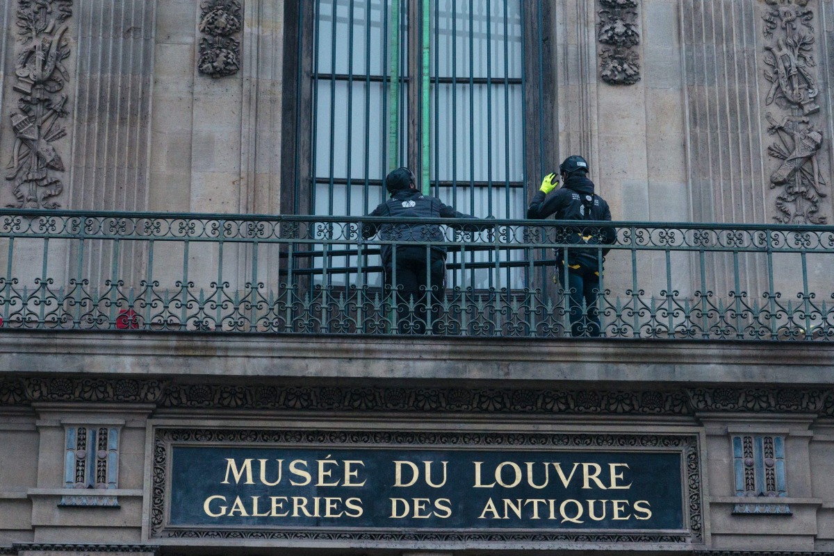 Workers install iron window guards on the window of the Gallerie d'Apollon (Apollo's gallery) of the Louvre Museum, on the Quai Francois Mitterrand side, in Paris on December 23, 2025 a few weeks after thieves used a furniture lift to break into the museum. Photo by Dimitar DILKOFF / AFP