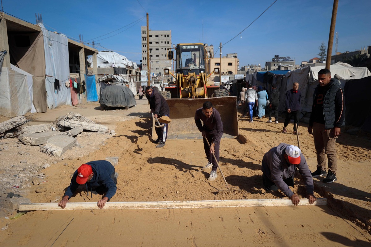 Palestinian municipality workers repair a road damaged during the war in the Nuseirat camp for the displaced in the central Gaza Strip on December 22, 2025. (Photo by Eyad Baba / AFP)
