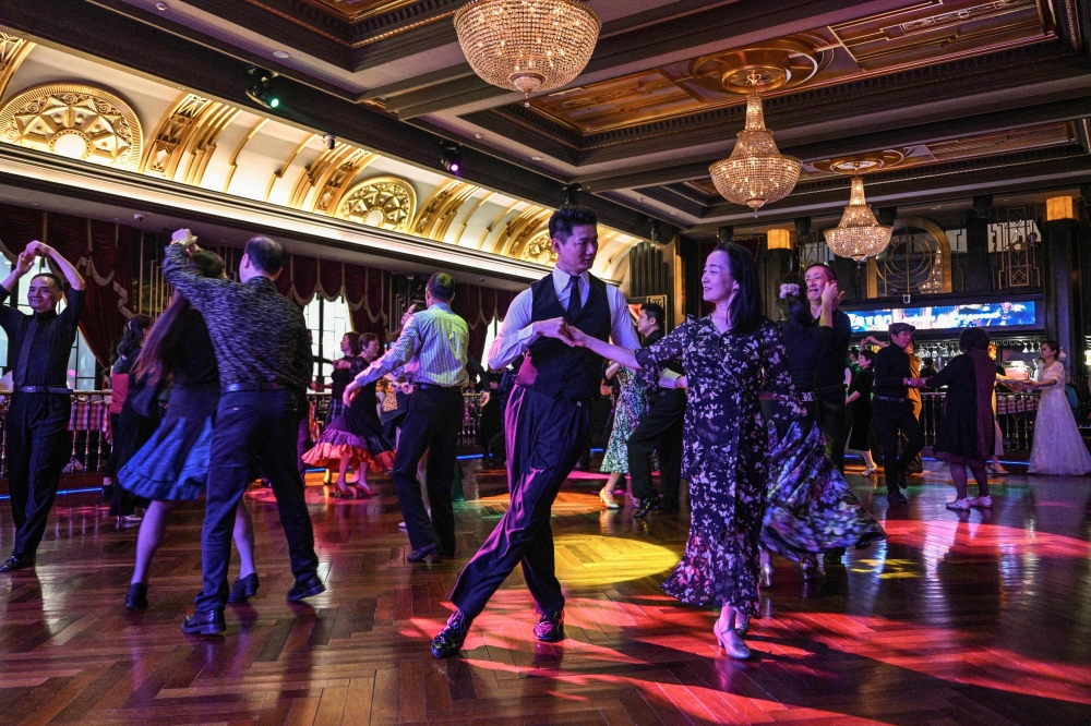 This photo taken on December 11, 2025, shows couples dancing at the Paramount Ballroom in the Jing'An district of Shanghai. (Photo by Hector Retamal / AFP)