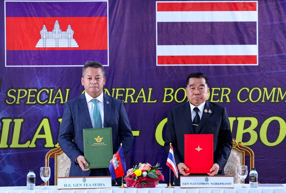 This handout photo released by Agence Kampuchea Press (AKP) on December 27, 2025 shows Cambodia's defence minister Tea Seiha (L) and Thailand's defence minister Nattaphon Narkphanit (R) posing with documents during the special General Border Committee (GBC) meeting at a border checkpoint in Thailand's Chanthaburi province. Photo by Agence Kampuchea Presse (AKP) / Agence Kampuchea Press (AKP) / AFP