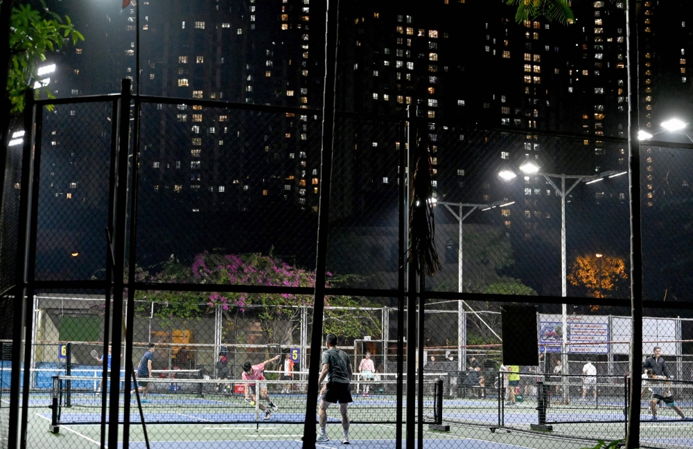 This picture taken on December 23, 2025 shows people playing pickleball in the playground of a residential area in Hanoi. (Photo by Nhac Nguyen / AFP) 