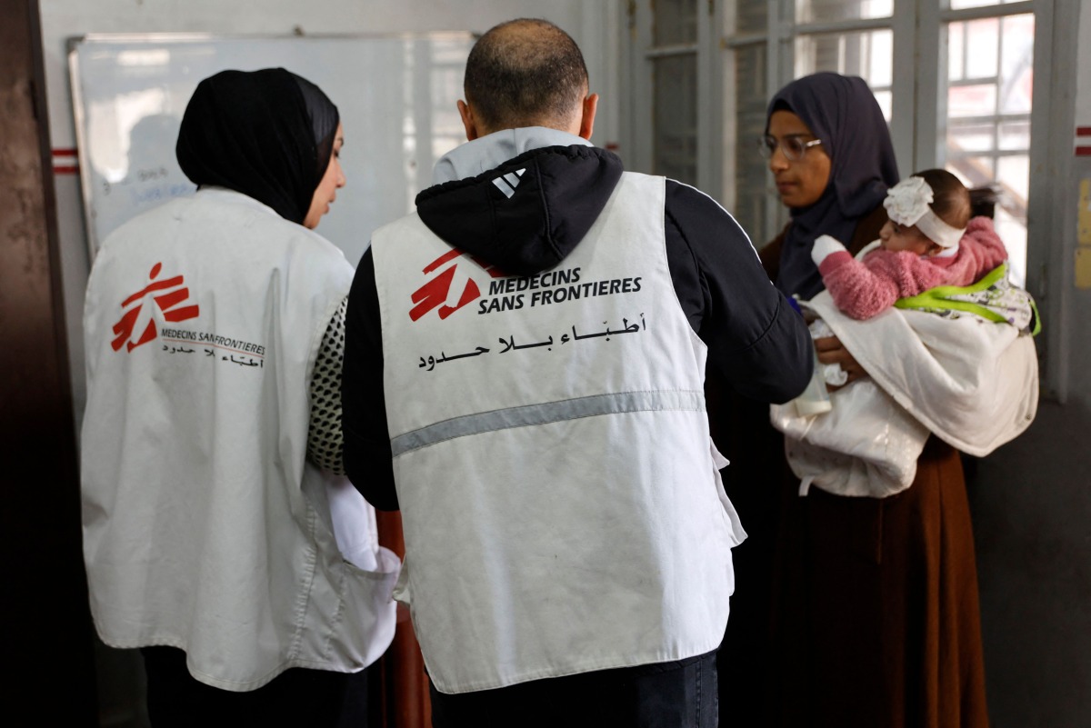A Palestinian woman arrives with a child at the Doctors Without Borders or Medecins Sans Frontieres (MSF) clinic, in the al-Rimal neighborhood of Gaza City on new year's Eve, December 31, 2025. (Photo by Omar AL-QATTAA / AFP)