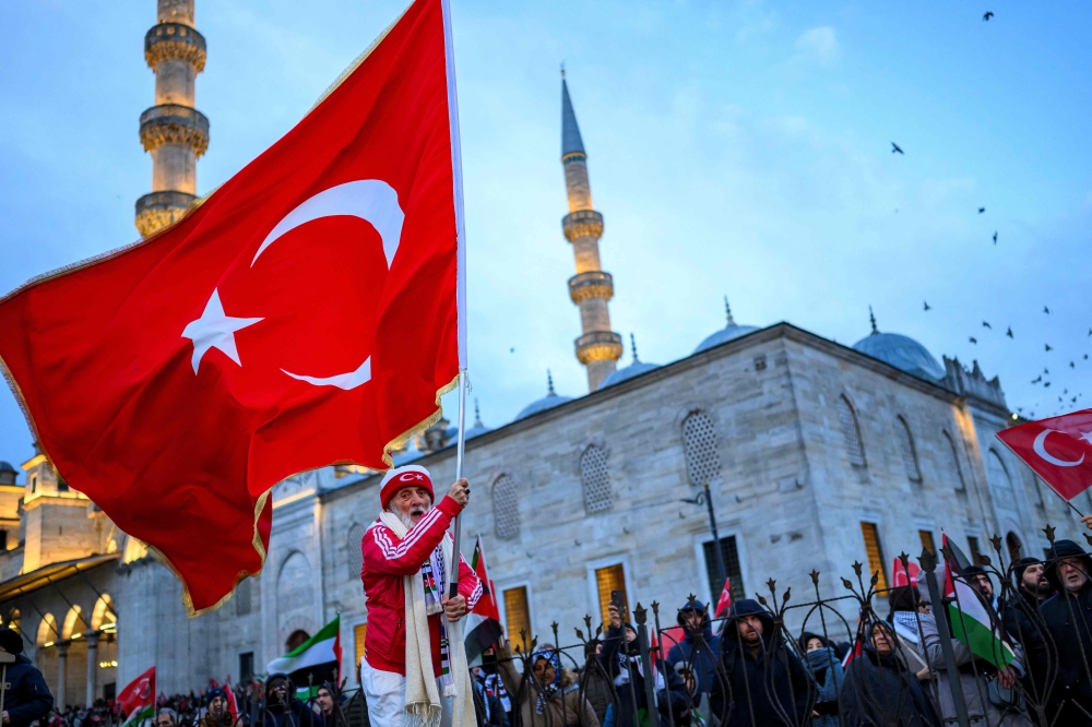 A man waves a Turkish flag as people demonstrate in solidarity with the Palestinian people amid the ongoing war in the Gaza  at the Galata Bridge in Istanbul on January 1, 2026. (Photo by Yasin Akgul / AFP)