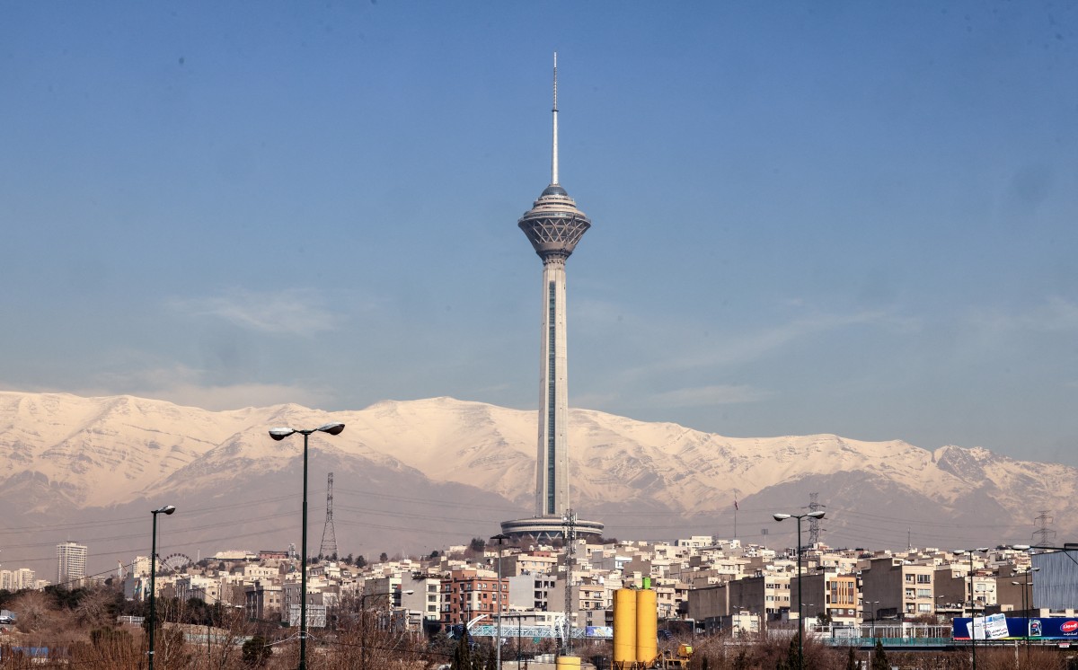 The Milad Tower is backdropped by the snow-covered Alborz Mountains, north of the capital Tehran on December 31, 2025. (Photo by Atta Kenare / AFP)
