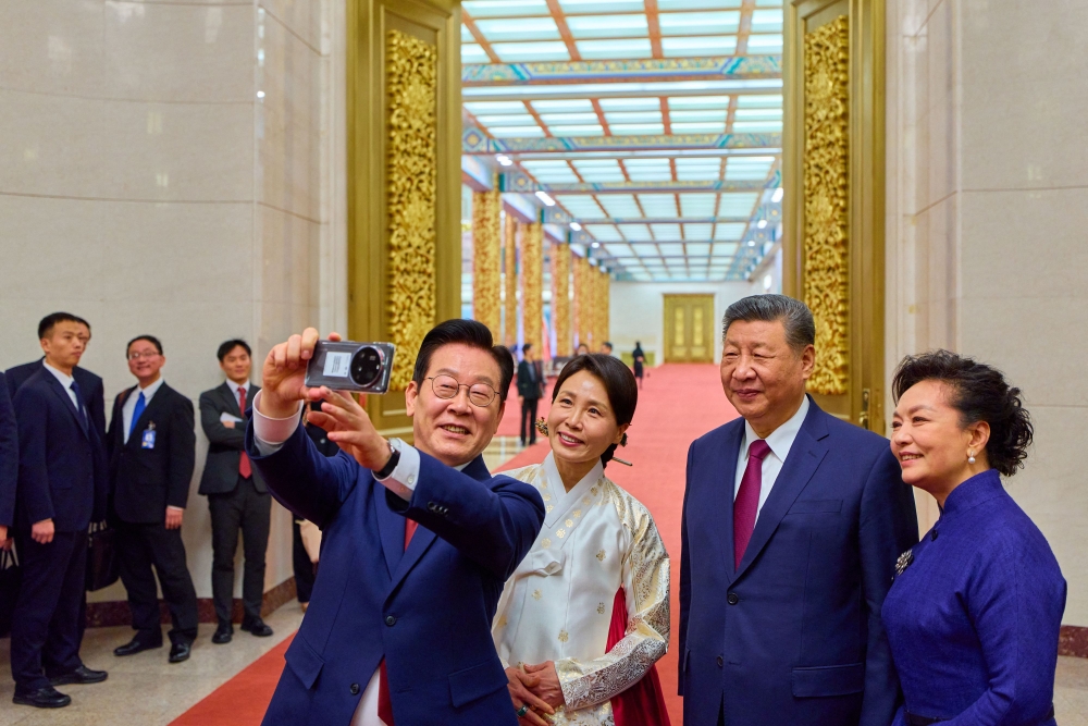 South Korea's President Lee Jae Myung (L) and his wife Kim Hea Kyung (2nd L) take a selfie with China's President Xi Jinping (2nd R) and his wife Peng Liyuan (R) after a dinner at the Great Hall of the People in Beijing on January 5, 2026. (Photo by YONHAP / AFP