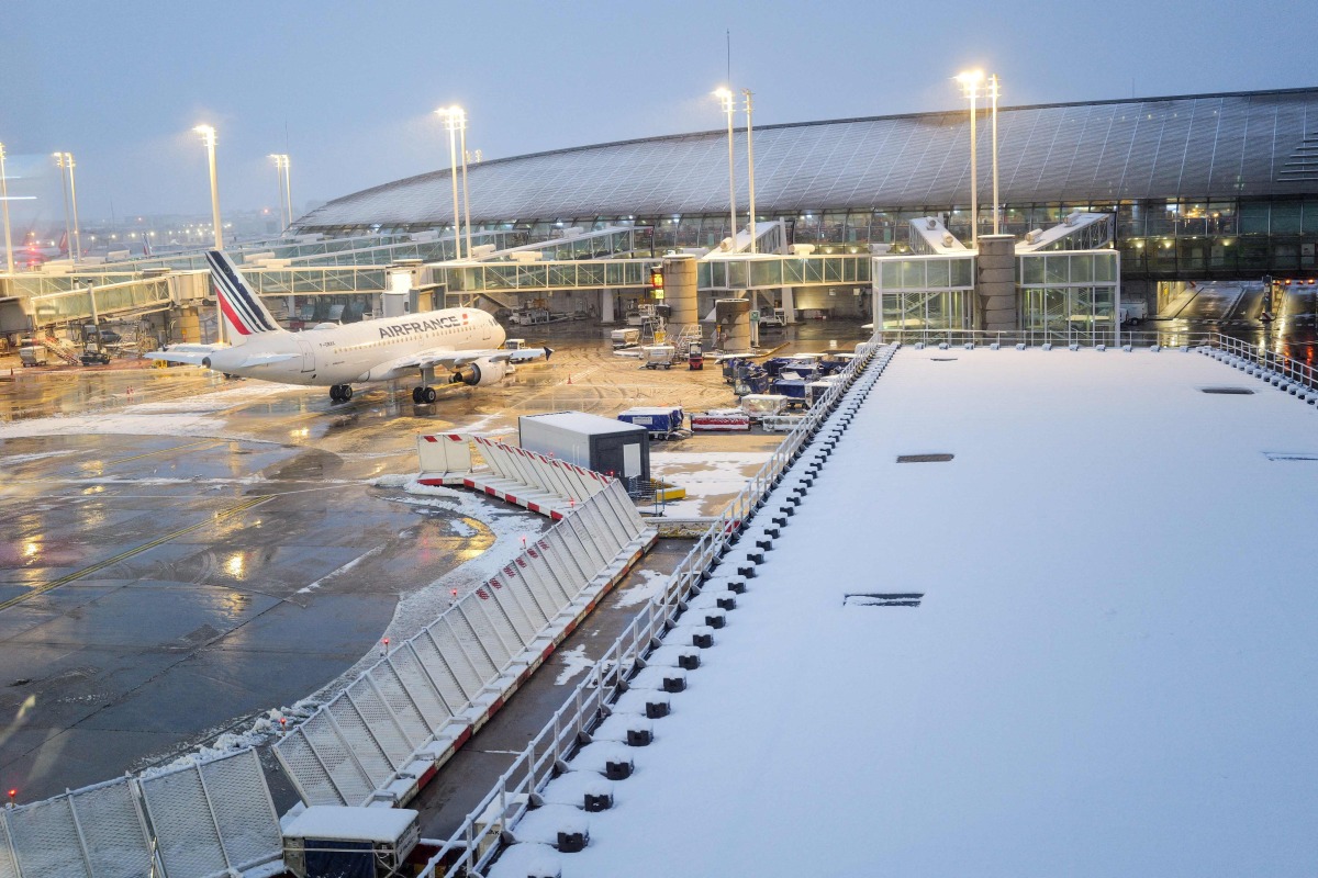 (FILES) This photograph shows an Air France aircraft with snow on the tarmac at the Roissy-Charles de Gaulle airport in Roissy-en-France, in the northern outskirts of Paris, on November 21, 2024. (Photo by Valery HACHE / AFP)