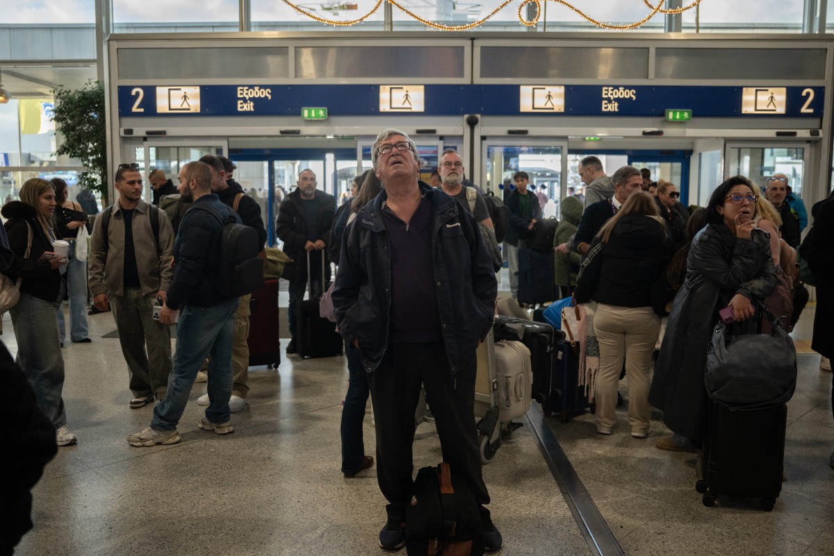 Passengers check screens for flight information as traffic is delayed or reported due to technical issues at a departure hall of Athens' Eleftherios Venizelos international airport in Spata near Athens, on January 4, 2025. Photo by Angelos Tzortzinis / AFP 
