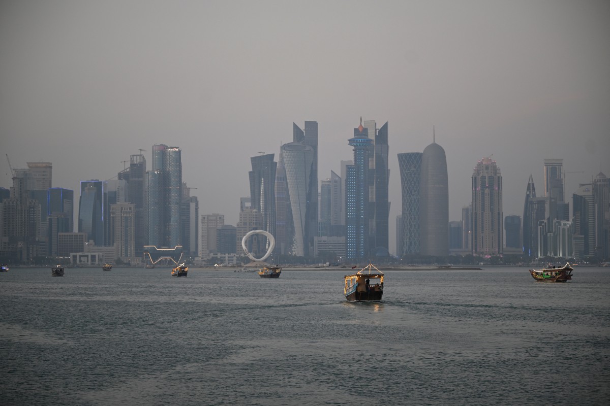 Tourists ride traditional boats along the corniche promenade in Doha on January 13, 2026. (Photo by Mahmud HAMS / AFP)
