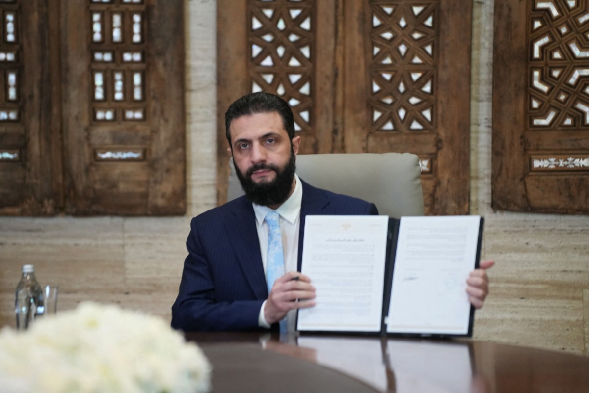 Syria's President Ahmed al-Sharaa signs an agreement at the Presidential Palace in Damascus on January 18, 2026. (Photo by Rami al SAYED / AFP)
